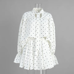 White polka dot dress on a mannequin against a gray background