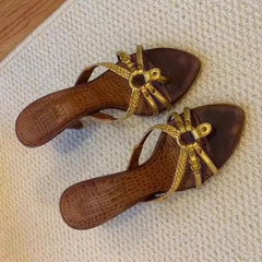 Pair of brown sandals with gold straps on a textured surface