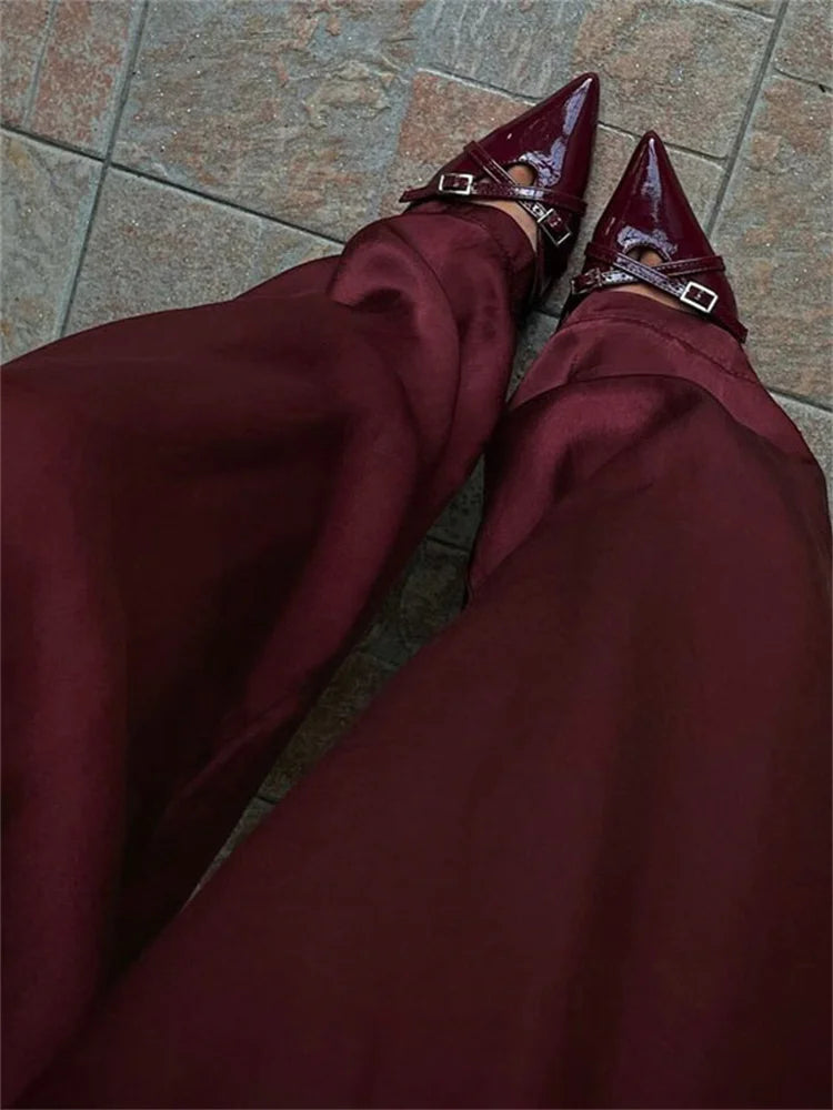 Burgundy high-waisted pants and pointed-toe shoes on a tiled floor.