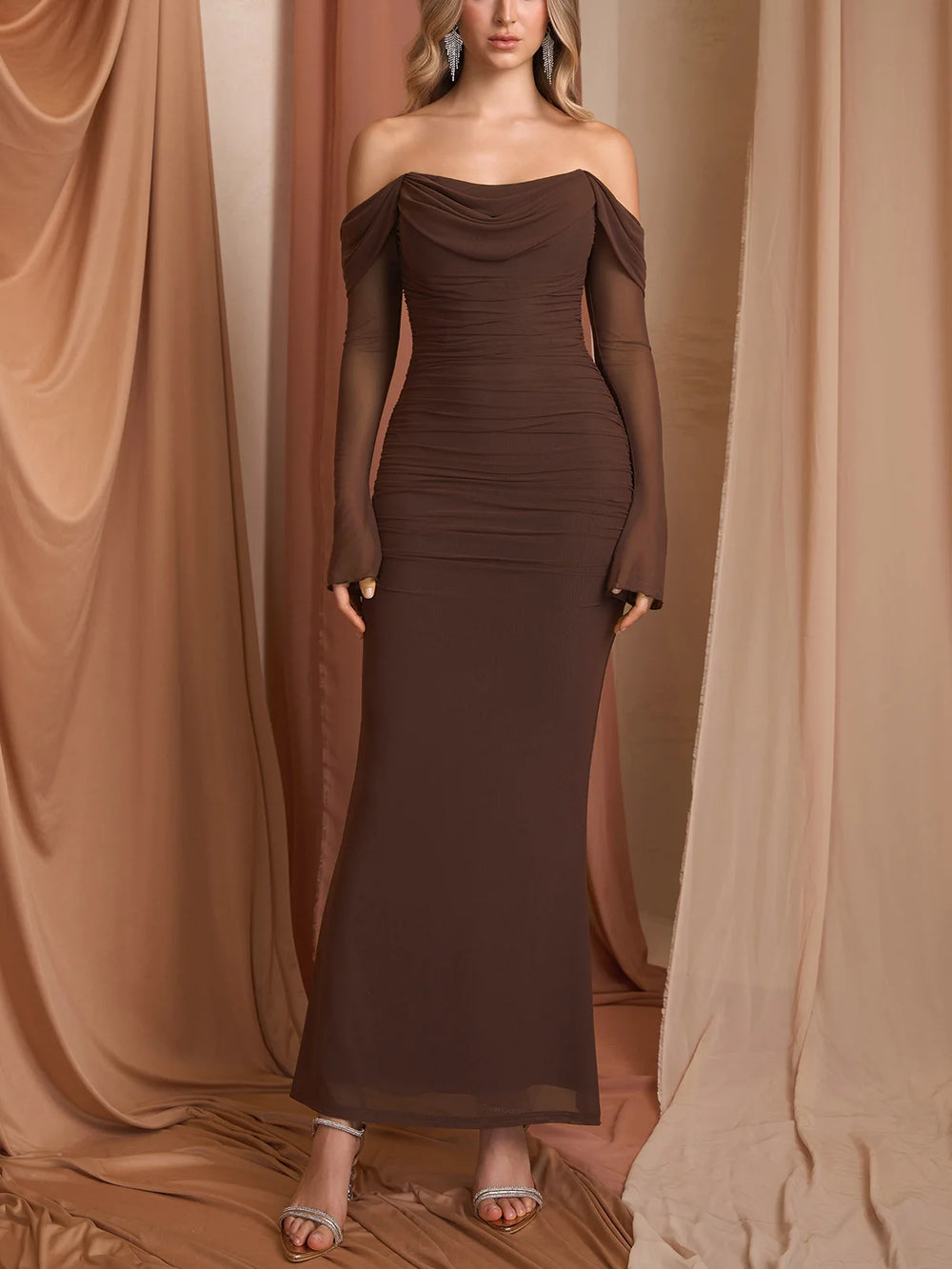 Woman wearing a brown off-shoulder gown against a beige curtain backdrop