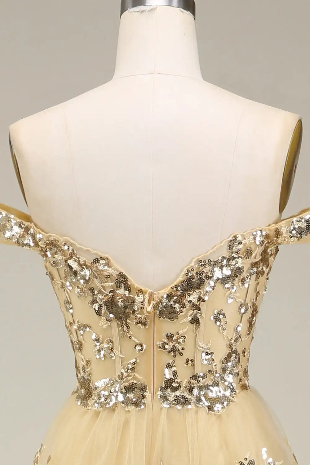 Beige evening gown with floral sequin detailing on a mannequin against a neutral background