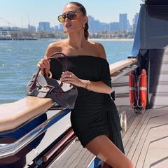 Woman in a black dress holding a handbag on a boat with a city skyline in the background