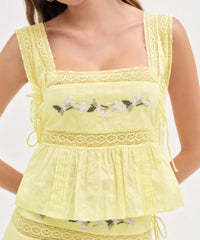 Yellow lace top with floral embroidery on a white background