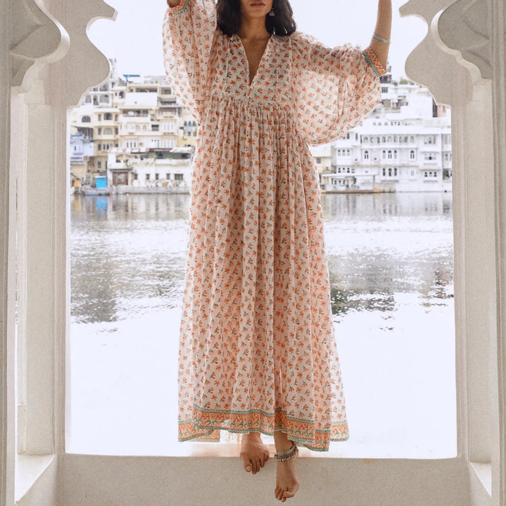Woman in a white floral print maxi dress posing by water