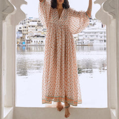 Woman in a white floral print maxi dress posing by water