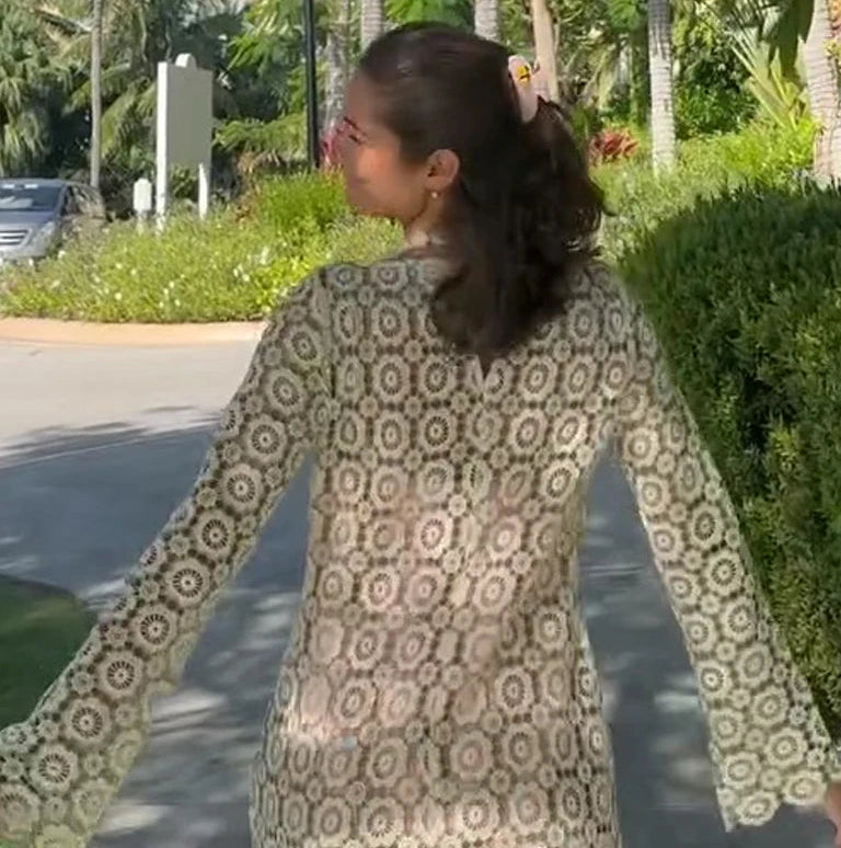 Woman wearing a patterned dress standing outdoors with greenery in the background