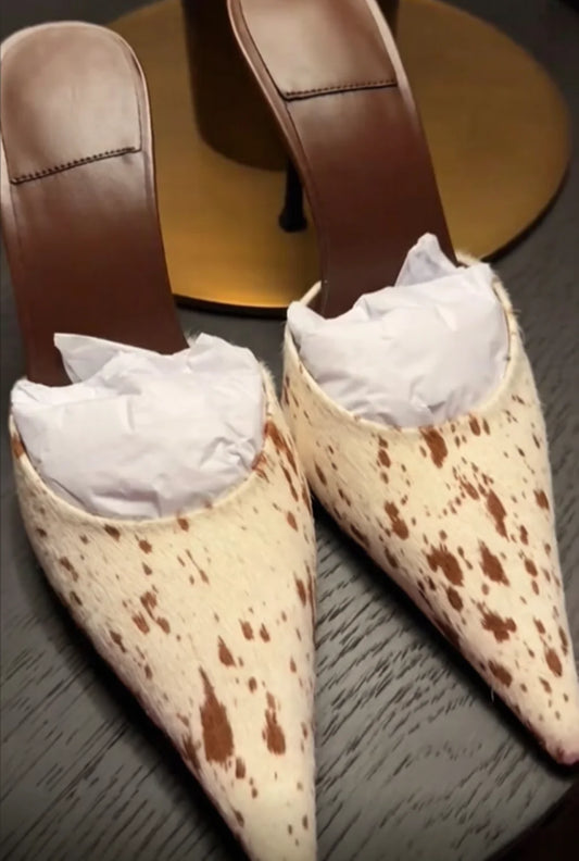 Pair of cow print stiletto heels with tissue stuffing