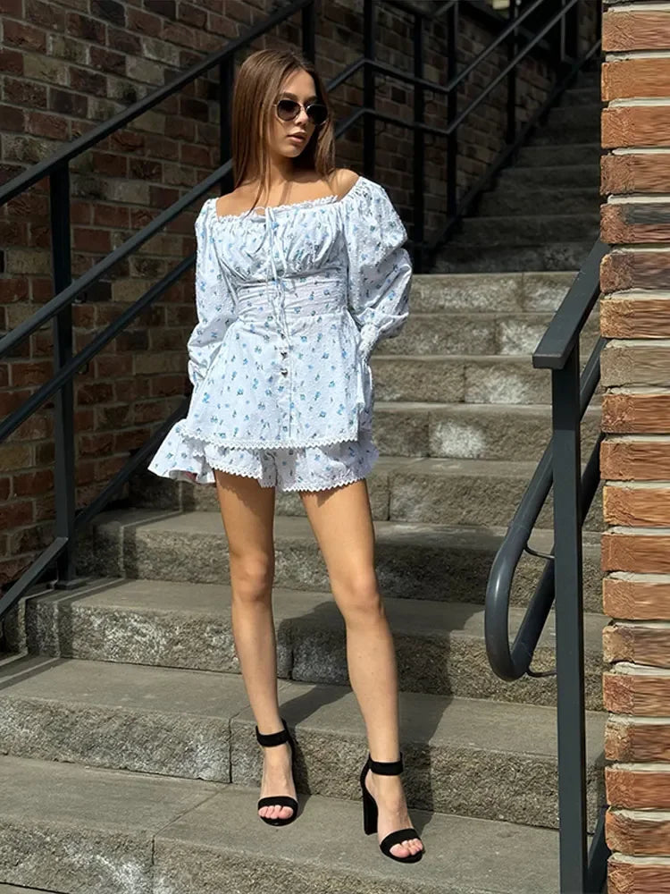 Woman in a light blue floral dress standing on stone steps with brick walls.