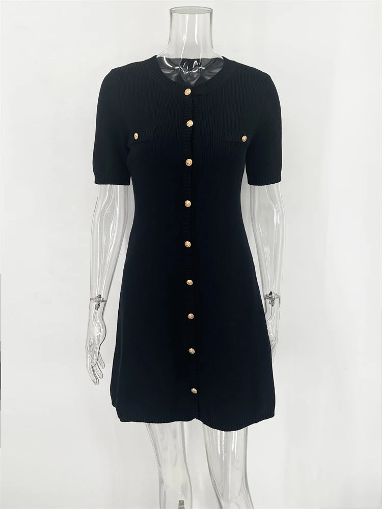 Black dress with gold buttons on a mannequin against a white background
