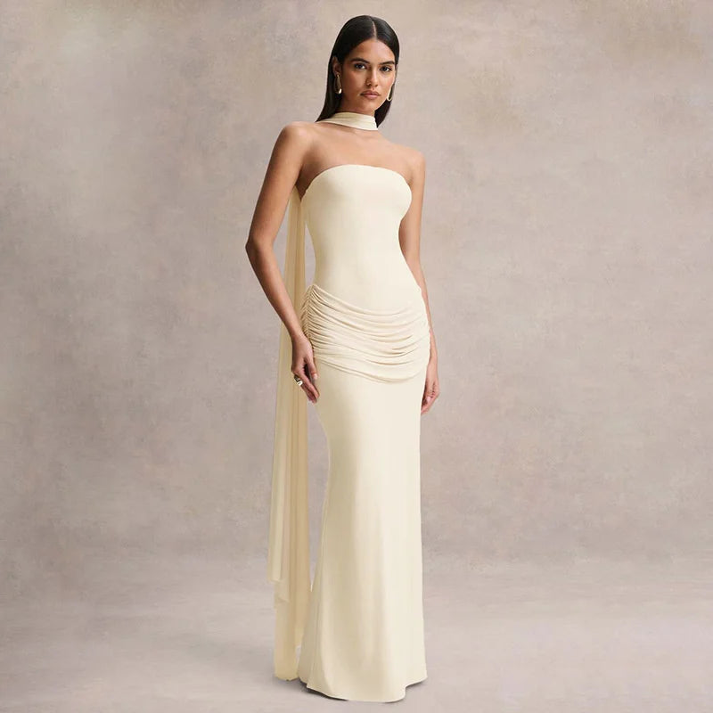 Woman wearing a long, strapless cream dress against a neutral background