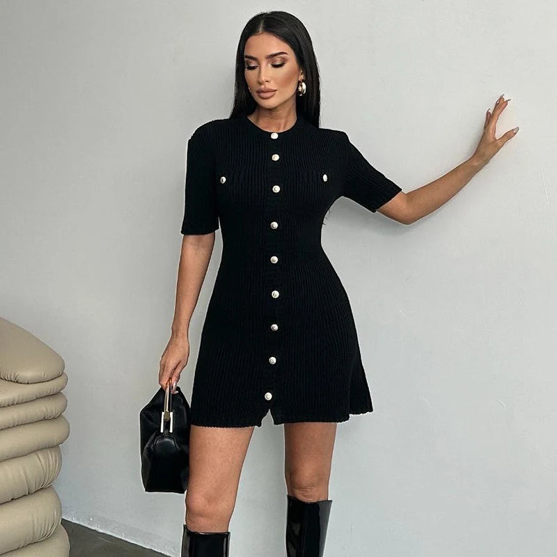Woman wearing a black dress with white buttons against a plain background