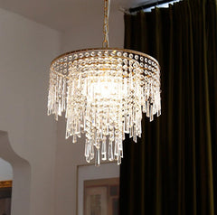 Crystal chandelier hanging in a room with a dark curtain.