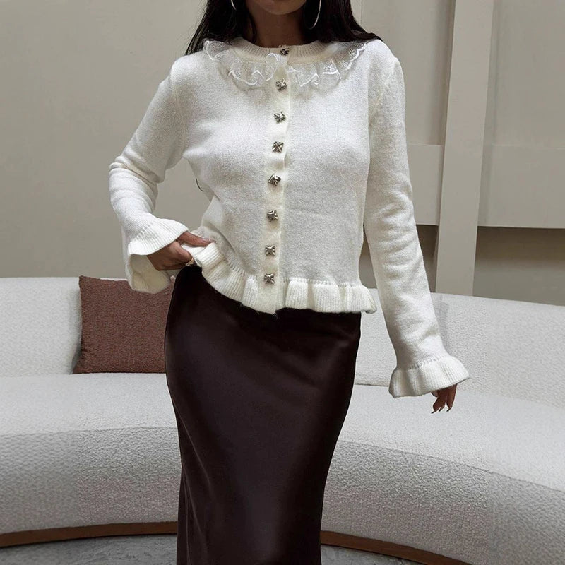 Woman wearing a white cardigan with decorative buttons in a living room setting.