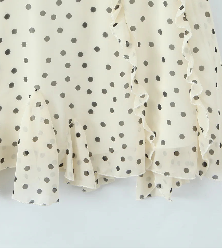 White blouse with black polka dots on a light gray background