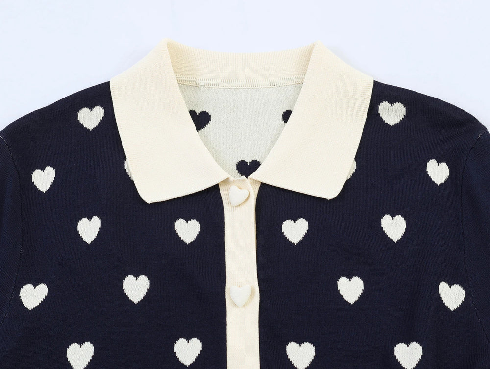 Close-up of the collar and button detail on the navy heart jacquard knit top.