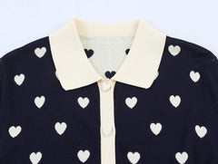 Close-up of the collar and button detail on the navy heart jacquard knit top.