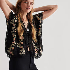 Woman wearing a black floral embroidered top against a white background