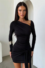 Woman wearing a black one-shoulder dress with long sleeves in an indoor setting.