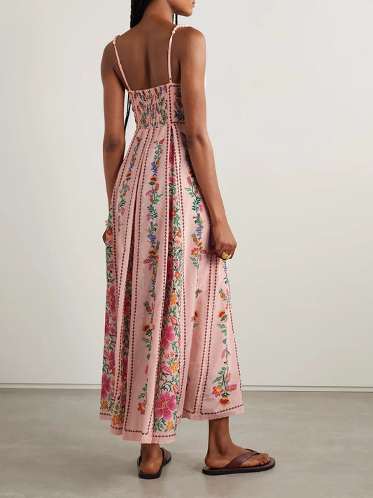 Woman wearing a floral pink dress with thin straps on a plain background