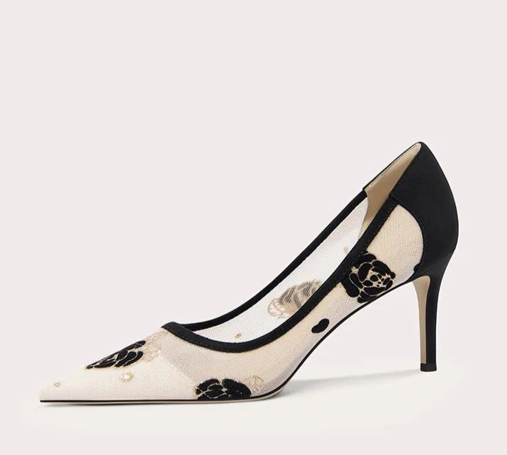 Black and white high-heeled shoe with floral design on a light gray background