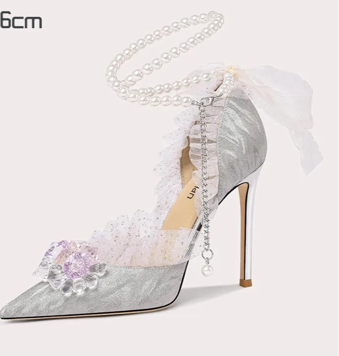 Silver high-heeled shoe with floral design and bow on a white background