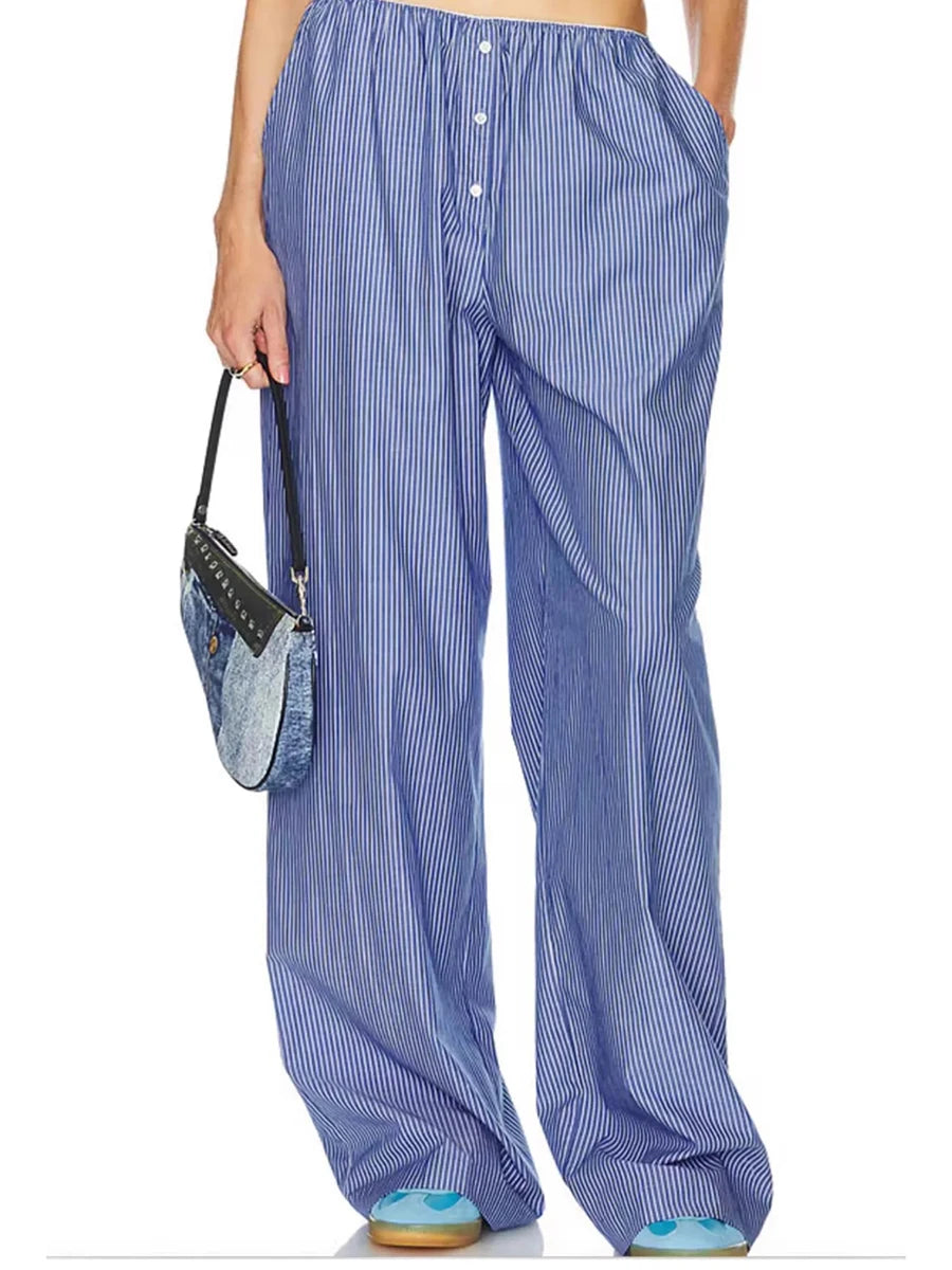Person wearing blue striped pants holding a denim bag on a white background