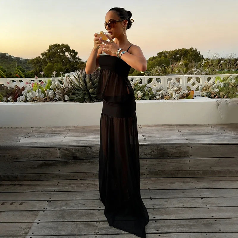 Woman in a long black dress standing on a wooden deck with a scenic background
