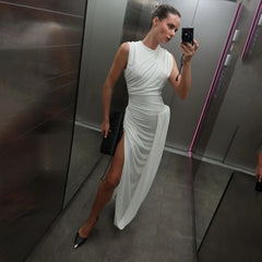 Woman in a white dress taking a mirror selfie in an elevator.