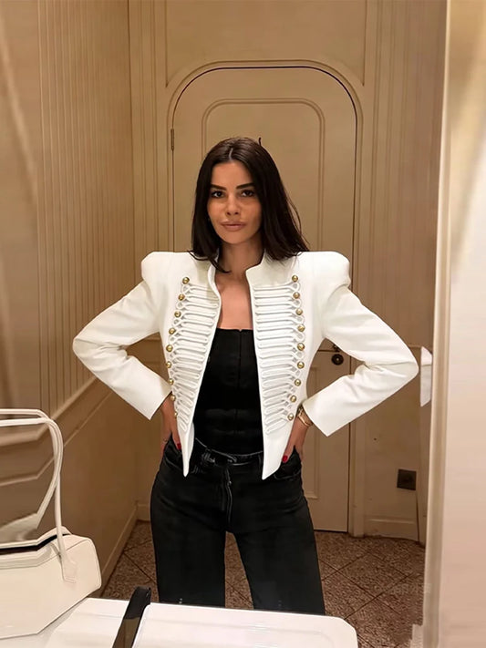 Woman wearing a white cropped military style jacket with gold buttons and cord braiding