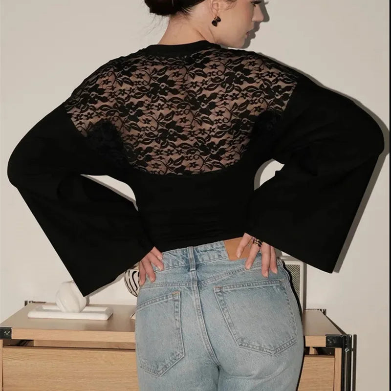 Person wearing a black lace top and light blue jeans in an indoor setting