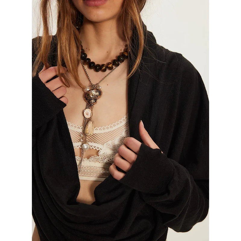 Person wearing a black cardigan over a lace top with visible jewellery.