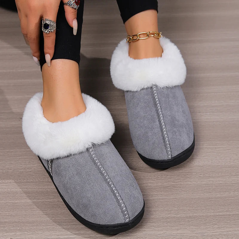 Gray slippers with white fur lining worn by a person on a wooden floor.