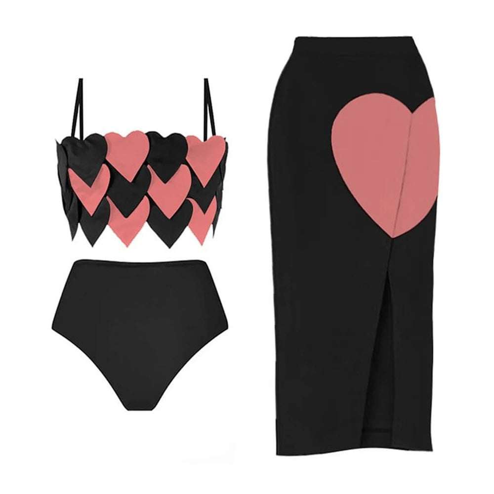 Black one-piece swimsuit with pink heart accents and a black beach skirt with a pink heart detail.
