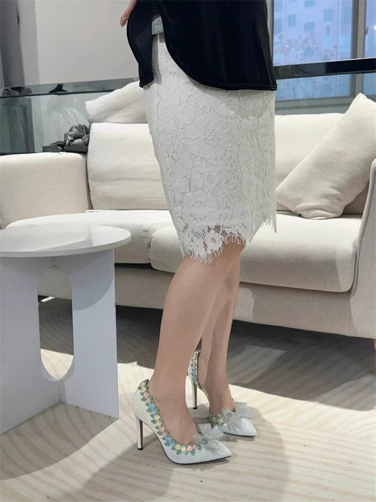 Person wearing a white lace skirt and high-heeled shoes in an indoor setting.