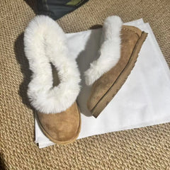 Pair of fur trimmed suede ballet flats on a textured surface
