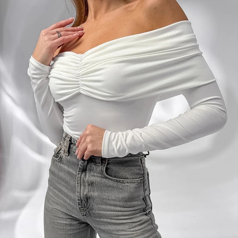 Person wearing a white off-shoulder top and gray jeans on a light gray background