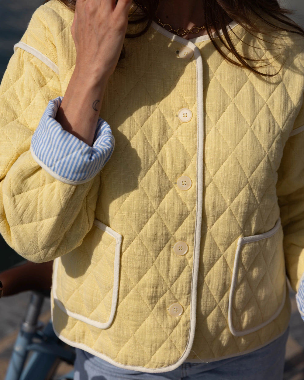 Person wearing a yellow quilted jacket with white buttons and trim.