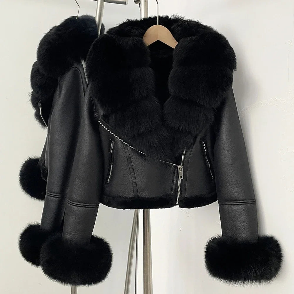 Black leather jacket with fur trim hanging on a rack against a white background