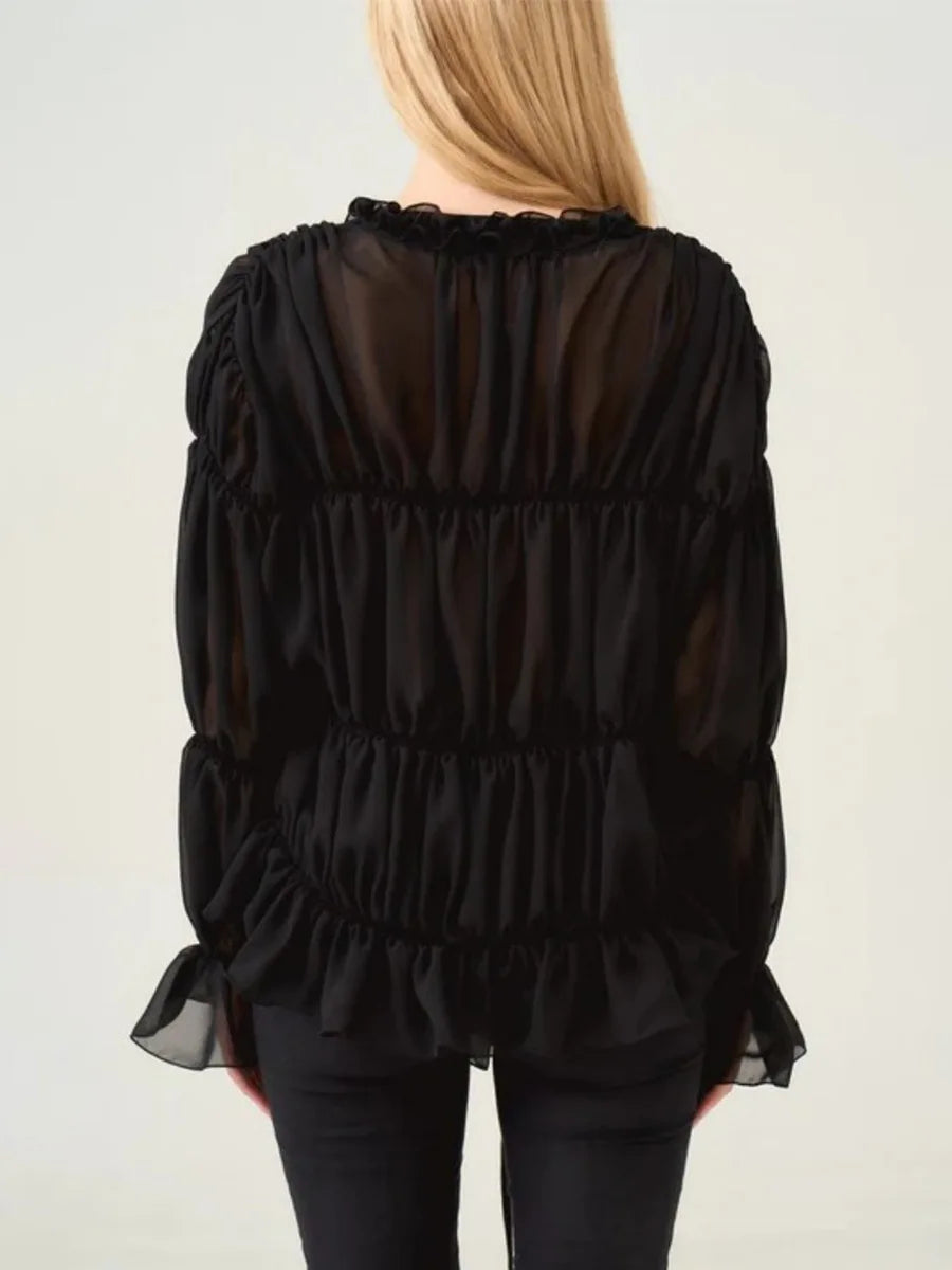 Black sheer blouse worn by a person on a plain background