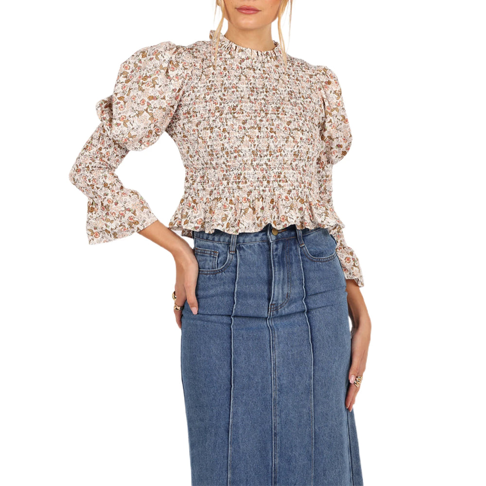 Woman wearing a floral blouse and blue jeans on a white background