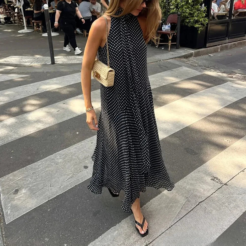 Woman in a black polka dot dress crossing a street with a crosswalk.