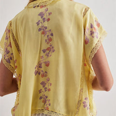 Yellow embroidered blouse with floral patterns on a plain background