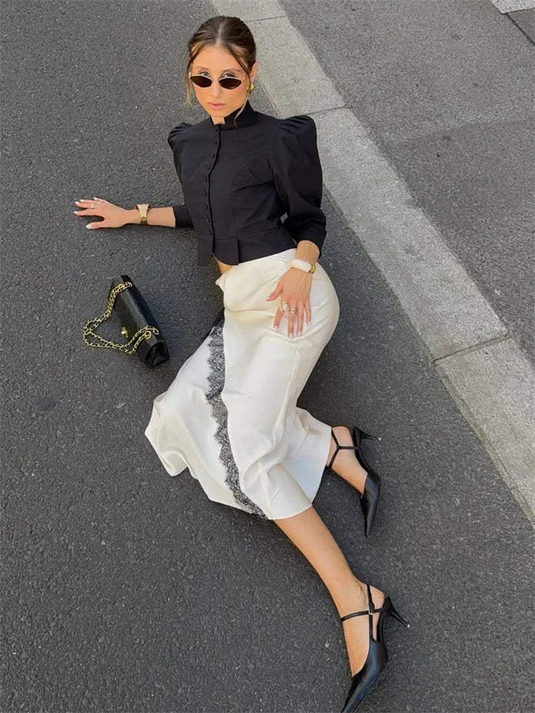 Woman in black top and white pants standing on a street