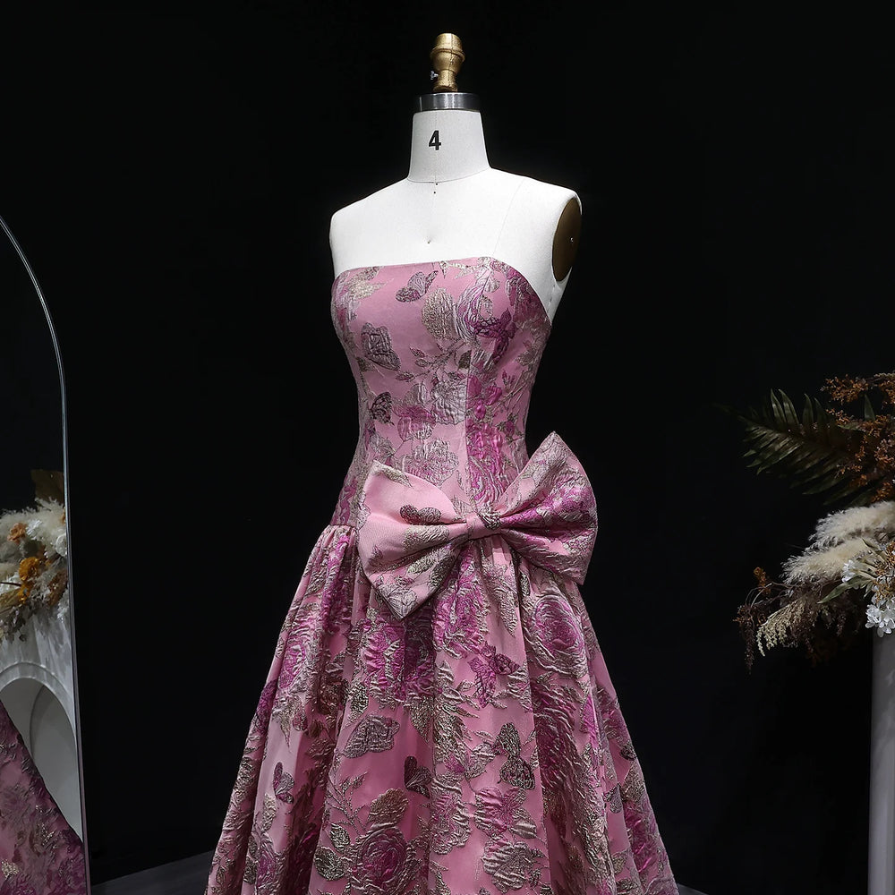 Pink floral dress with a large bow on a mannequin against a black background