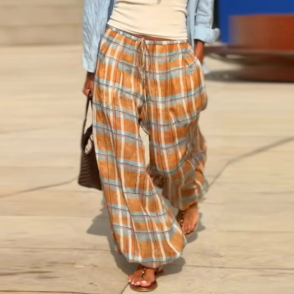 Person wearing plaid pants walking on a wooden deck.