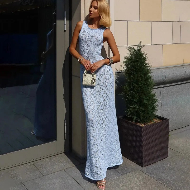 Woman in a light blue lace dress standing outdoors next to a building.