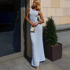 Woman in a light blue lace dress standing outdoors next to a building.
