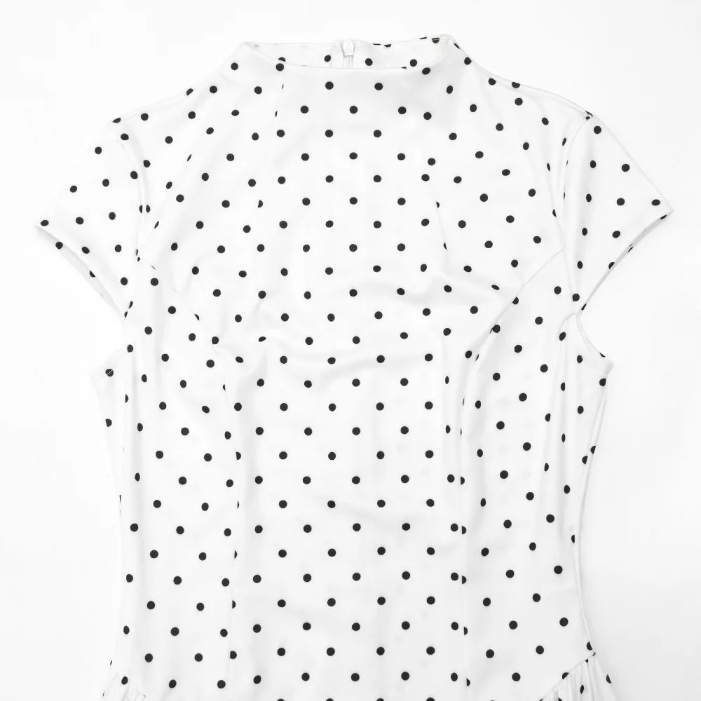 White sleeveless top with black polka dot pattern on a white background