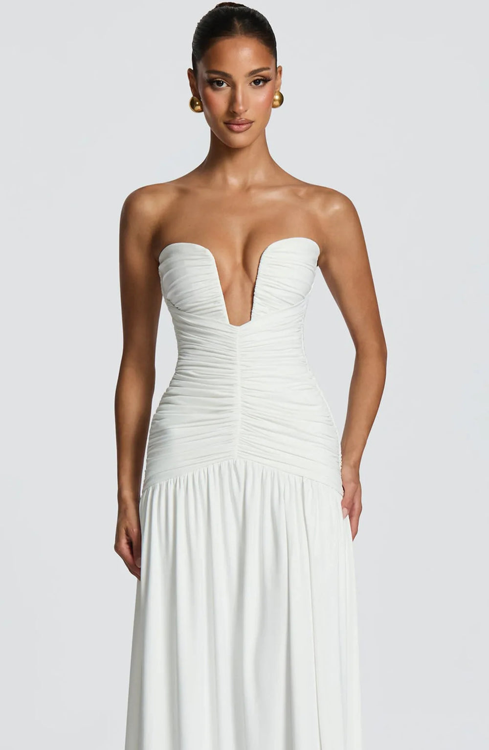 Woman wearing a strapless white gown on a plain background