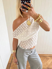 White polka dot mesh one-shoulder crop top styled with grey trousers